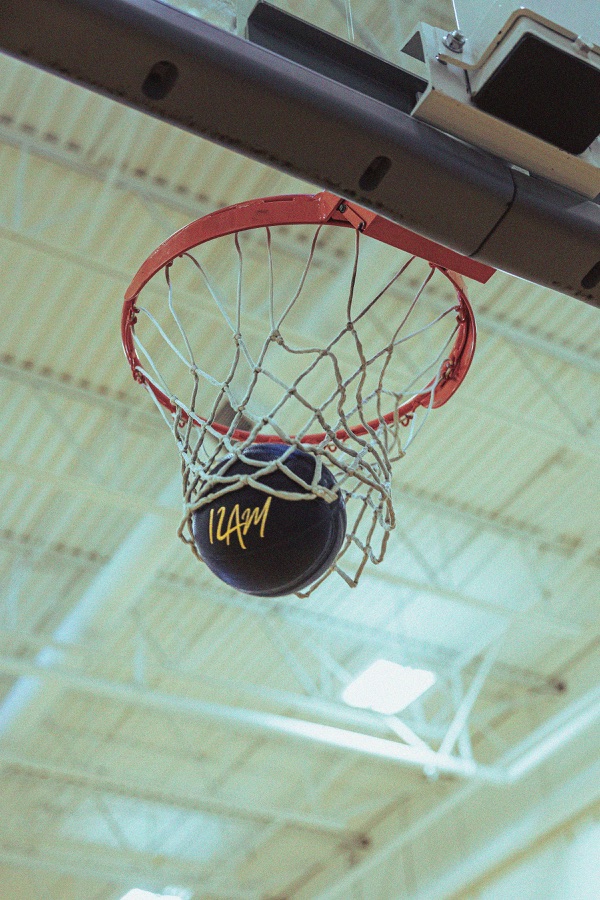 A matte-black 12AM basketball dropping through a basketball net